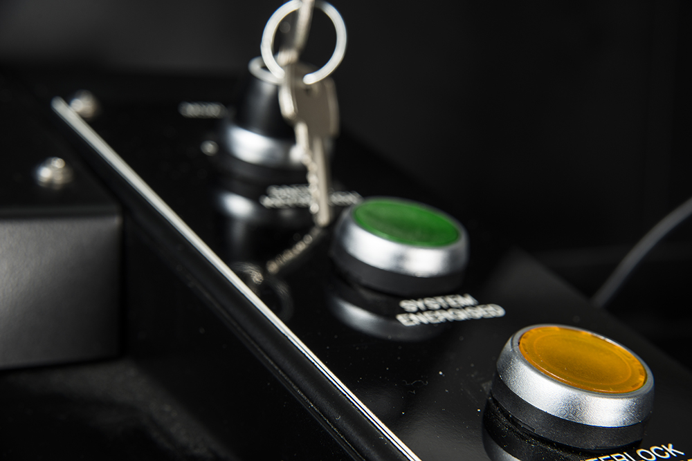 Close-up of an industrial inspection machine's control panel with key switch and buttons, used in catalytic converter quality control.