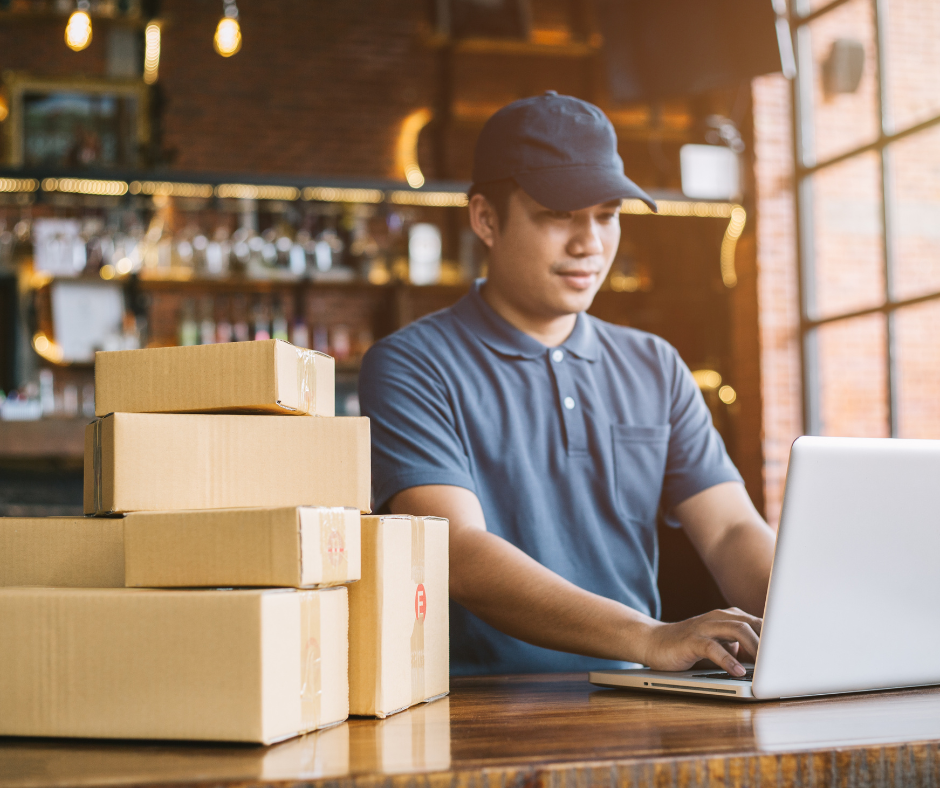 Ecommerce worker managing parcel deliveries on a laptop, highlighting the growing need for x-ray screening solutions in response to increased online shopping volumes.